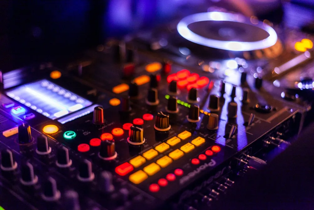 Close-up of an illuminated DJ controller — lit knobs and buttons against a dark background